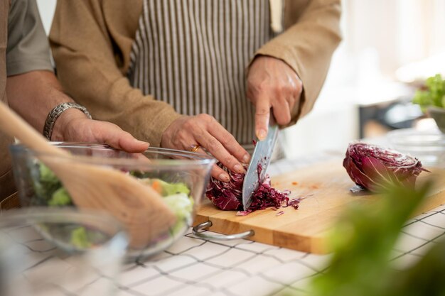 写真 妻が野菜を切りキッチンで夫と健康的な朝食を作っている