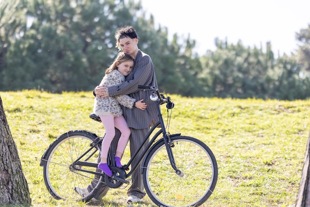 写真 自転車に座っている女性と娘が抱きしめ合っている