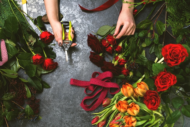 Фото Женщина собирает букет весенних цветов на каменном столе. флорист на рабочем месте
