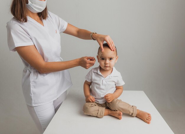 女医が男の子の額に石膏を室内に貼る。スタジオ写真。健康の概念