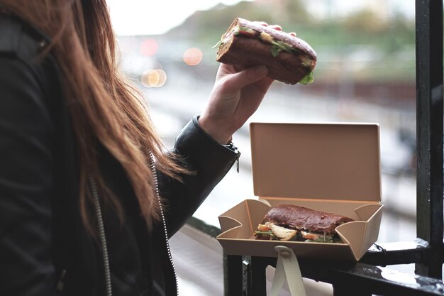 写真 箱に入ったサンドイッチを食べる女性