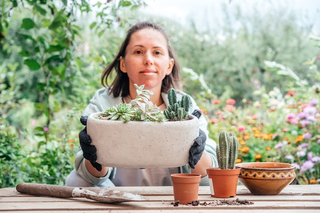 写真 多肉植物とサボテンを屋外で植え替える女性の庭師