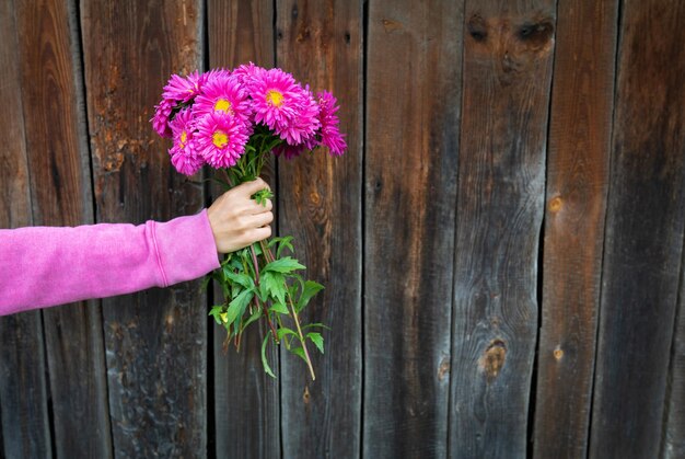 写真 女性が木製の壁の背景にピンクの花束を手に持っています