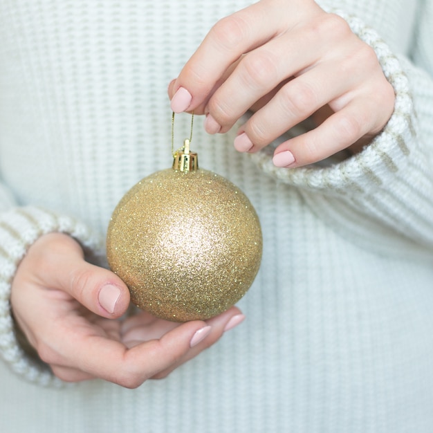 사진 그녀의 손에 장난감 황금 공을 들고 가벼운 따뜻한 모직 스웨터에 여자, 복사 공간, 선택적 초점