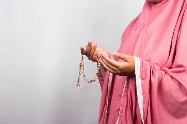 Фото Женщина в розовом халате держит в руках четки.