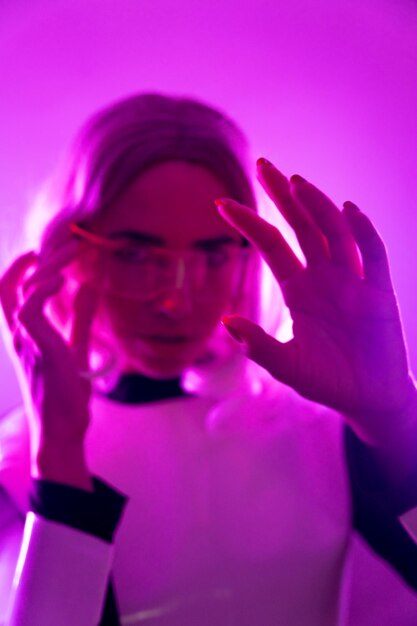 Фото Женщина в костюме и футуристических очках с розовыми огнями, виртуальная или метавселенная, смотрит в камеру