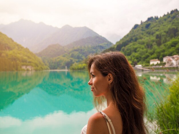 ドロミテ、イタリアの紺碧の山の湖の橋の上に夏のドレスを着た女性が立っています