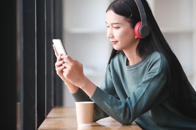 写真 女性がコーヒーと携帯電話を持ってテーブルに座っています