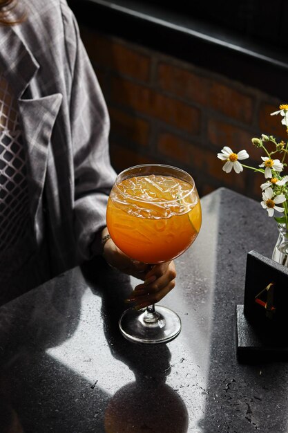 写真 女性がオレンジ ジュースのグラスを持ってテーブルに座っています。