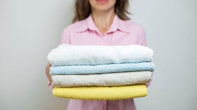 Фото Женщина держит аккуратно сложенные чистые полотенца.