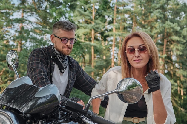 バイクのミラーを覗く女性 一緒に旅行する中年夫婦