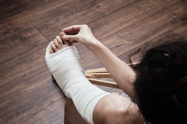 写真 女性が手で骨折した足のつま先をマッサージする骨折した足の後のホームリハビリテーション