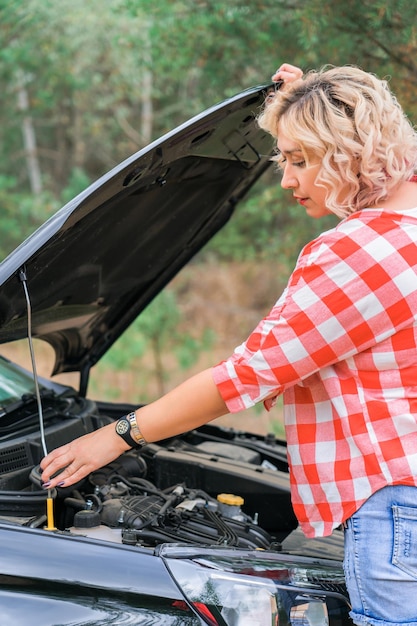 写真 女性が車のクローズ アップのボンネットを開きます