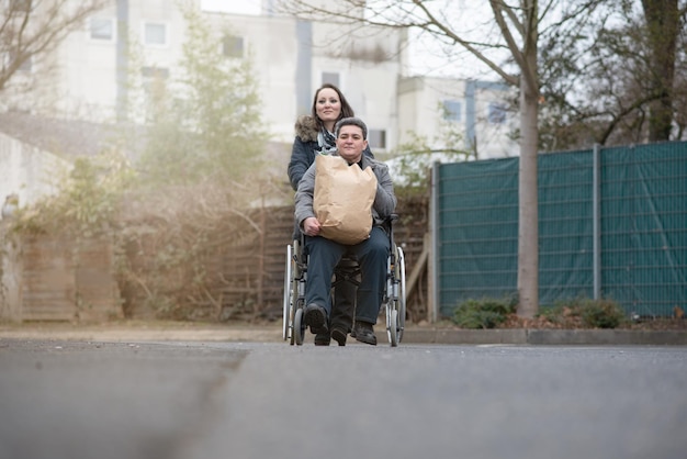 写真 女性がショッピングの後車椅子に乗っている身体障害者を押す