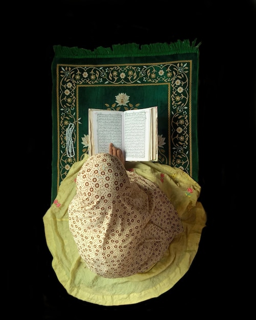 Фото Женщина читает книгу со словом коран на ней