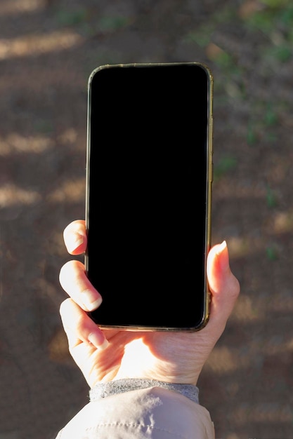 写真 女性の手が黒い画面の電話を持っている広告を出す場所のある電話を手に持っている