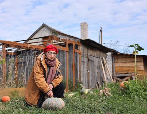 写真 a woman sits in front of a wooden house with a pumpkin in front of it