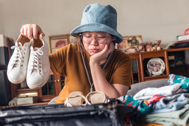 사진 모자를 쓴 여성은 휴가를 떠나기 위해 운동화 선택을 망설이고 있다.