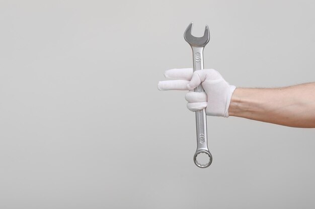 Фото Рабочий строитель ремонтник ремесленник руки с защитной перчаткой держит ключ на белом фоне мок-ап копирование пространства
