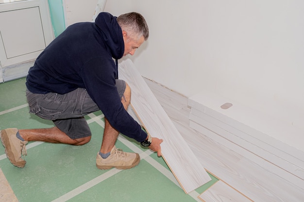 Фото Рабочий, соединяющий ламинат во время ремонта дома.