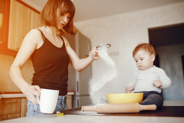 写真 若くて美しいお母さんが、小さな息子とともに、台所で食べ物を準備しています