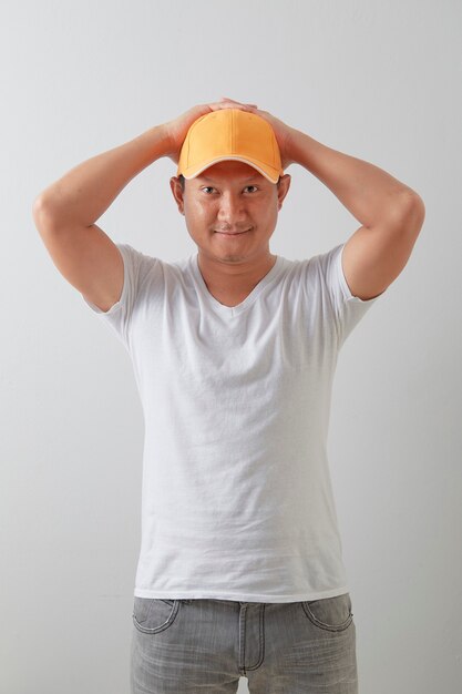 사진 밝은 회색 표면에 주황색 모자를 쓰고 젊은 아시아 배달 남자