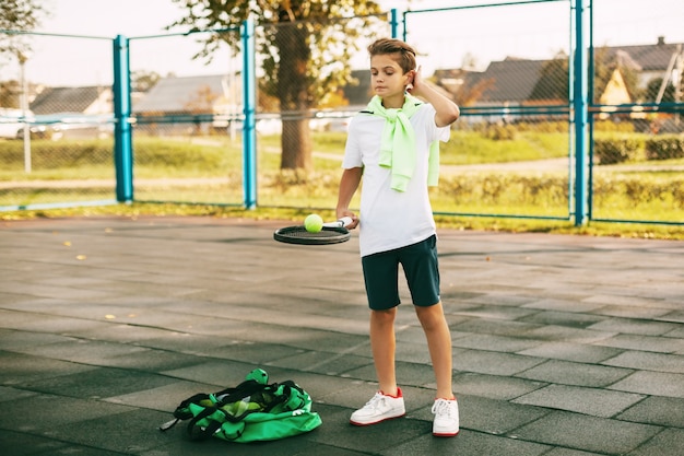 写真 若いアスリートがボールを乗せたテニスラケットを持っています。テニスプレーヤーはトレーニング前にウォームアップします