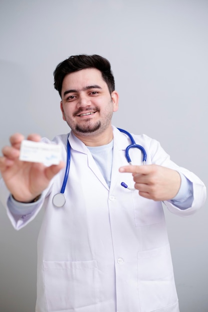 사진 젊은 의사가 한 손에 약을 들고 손가락으로 보이고 있다