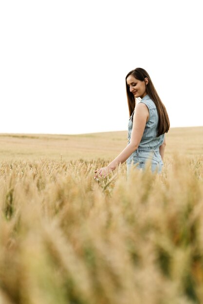 Фото Молодая девушка находится на огромном пшеничном поле и касается колосьев пшеницы. органическая пшеница. большое аргаровое поле. сельскохозяйственный бизнес. девушка идет по пшенице