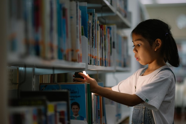 写真 若い女の子が図書館で本を見ている