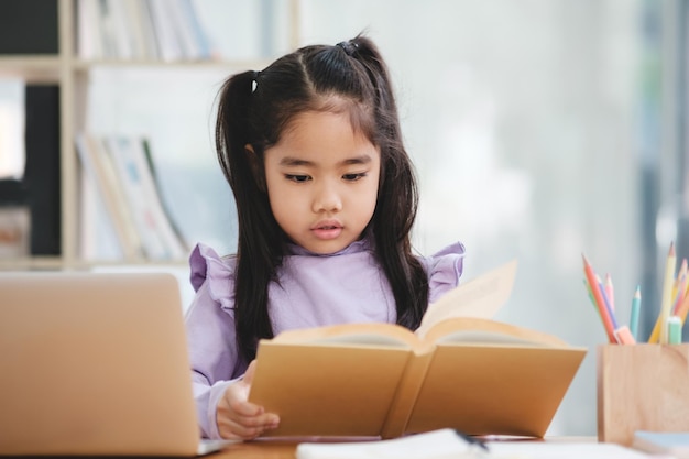 写真 若い女の子が机に座って本を読んでいる