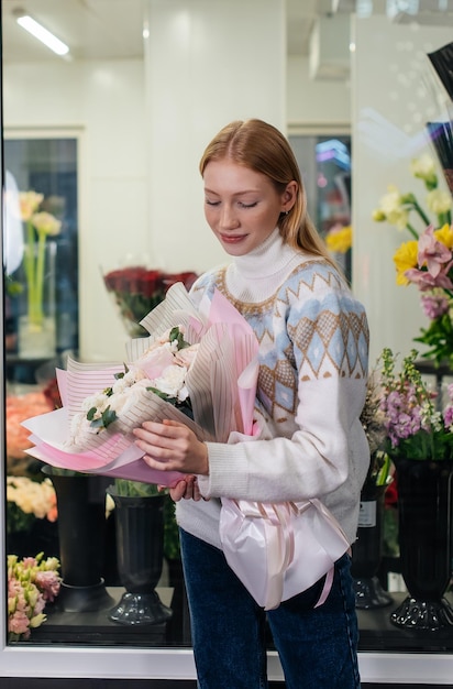 写真 居心地の良いフラワーショップを背景に美しいお祭りの花束でポーズをとる少女フローリストリーとフラワーショップでの花束作り中小企業