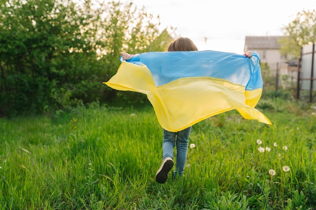 Фото Молодая девушка бежит с украинским флагом фото девушки, бегущей с украинским флагом в качестве накидки