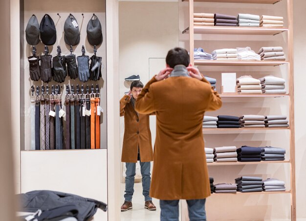 사진 한 젊은이 가게 에서 코트 를 입으려고 한다