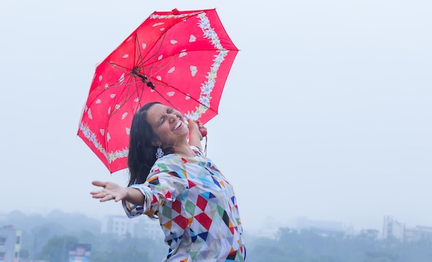 우산을 들고 인도의 우기 동안 비오는 날씨를 즐기는 젊은 여성