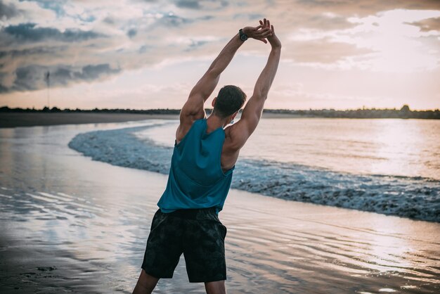 写真 若い男は、ビーチで日没時にビーチで運動します。温かみのある色