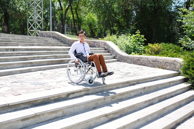 Фото Молодой человек в инвалидной коляске, который не может спуститься по лестнице.