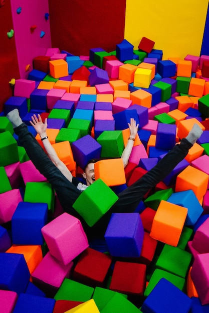 Фото Молодой человек или мальчик, отец играет и прыгают мягкими кубиками в