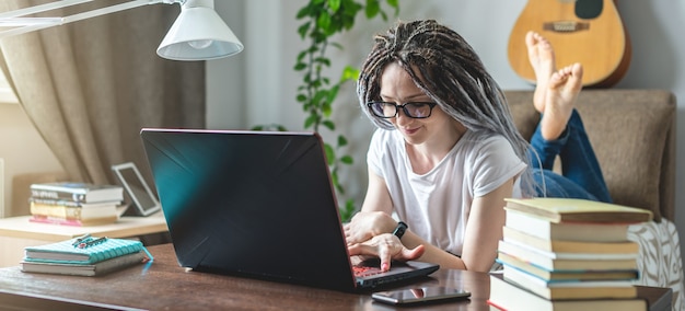 写真 若い現代の女性従業員は、ラップトップを使用して部屋で自宅でリモートオンラインで働いています