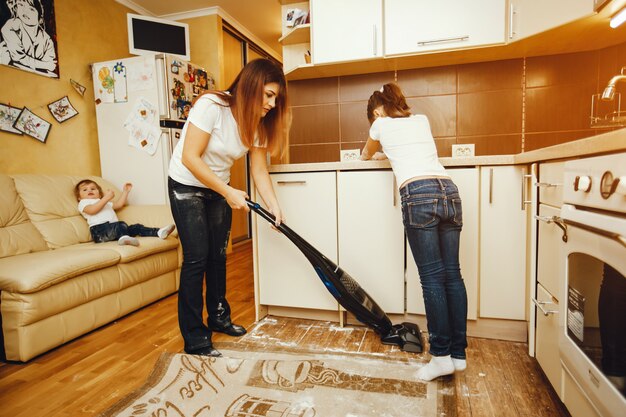 写真 彼女の子供と一緒に小麦粉の台所で掃除する若い母親