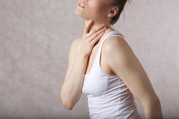 写真 30〜40歳の若い女性は、喉の痛みがあることを示しています。テキスト用の空き容量。