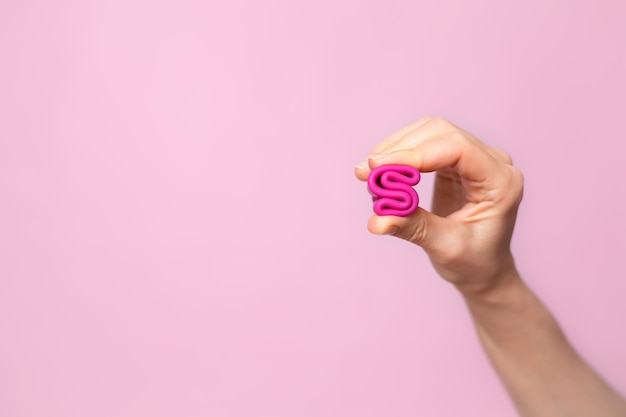 Фото Молодая женщина складывает в руке розовую менструальную чашу розовый цвет фона место для текста экологичный силиконовый женский 39-й цикл здоровья фото высокого качества
