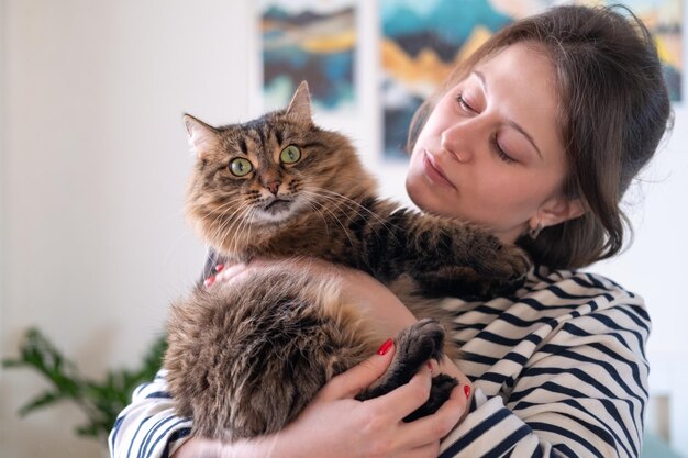 写真 若い女性が愛するシベリアの猫を抱きしめる 横の写真