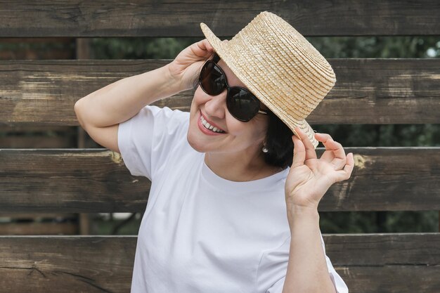 写真 草の帽子とサングラスを着た夏の服を着た若い女性が背景に立っています