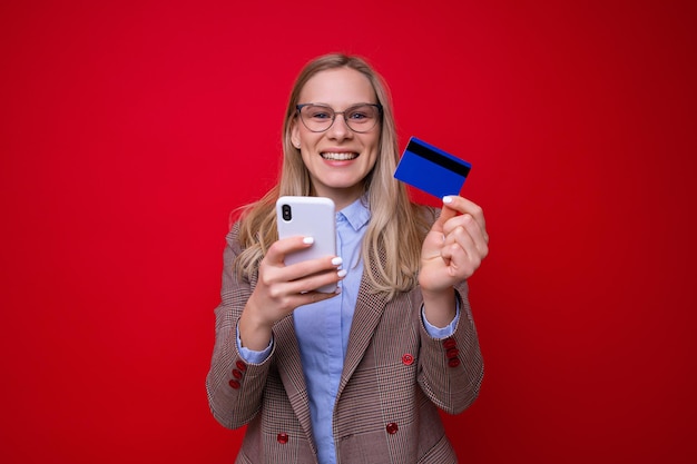Фото Молодая женщина делает покупки в интернете на красном фоне