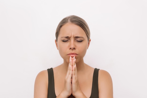 Фото Молодая женщина молится с закрытыми глазами и сложенными руками, благодарит, желает, просит помощи.