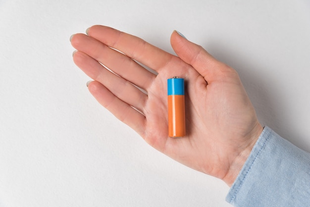 AA alkaline battery lying on the women's hands. Generic accumulator on white .