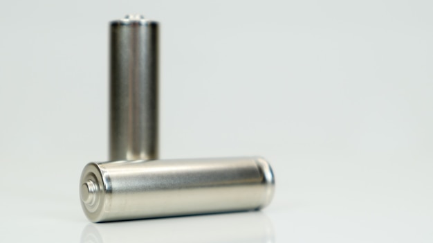 AA alkaline rechargeable batteries on white glossy background with reflection. Close up two empty batteries with copy space.