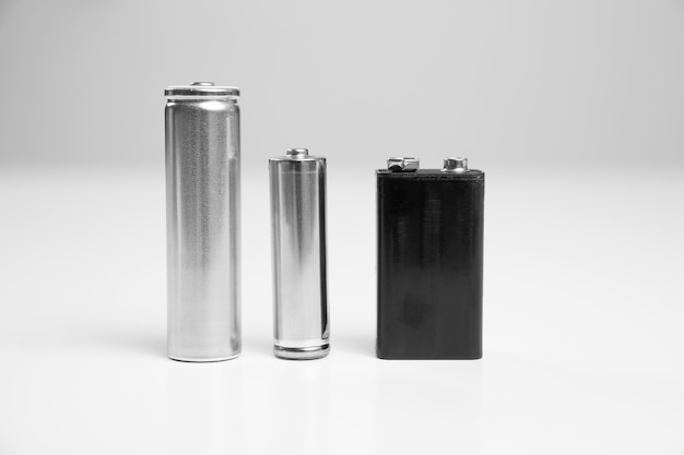 Фото aa и литий-ионный аккумулятор 8650 серебристый, батарея 9v черного цвета на белом фоне. одноразовые батарейки и аккумуляторы.