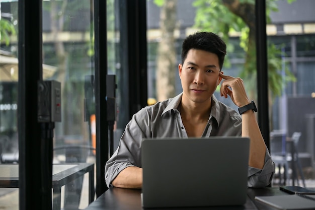 Aa businessman sits in a modern loft coffee shop with his laptop computer